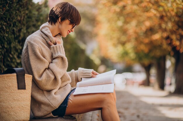 公園に座って読書をしている若い女性