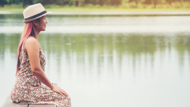 부두에 앉아서 강을보고 젊은 여자.