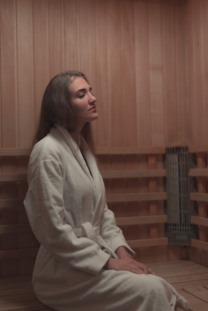 Free photo young woman sitting relaxed in a wooden sauna