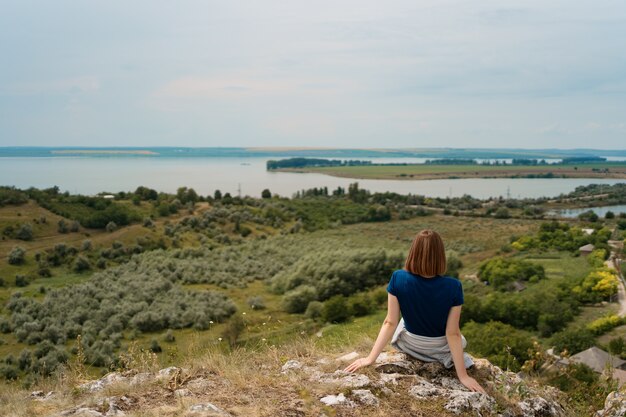 平和な瞬間を楽しんでいる岩の上に座っている若い女性。