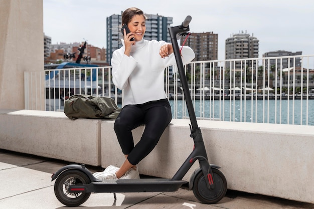 Young woman sitting next to a scooter