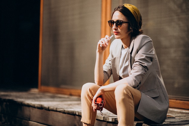 Young woman sitting and smoking ecigarette