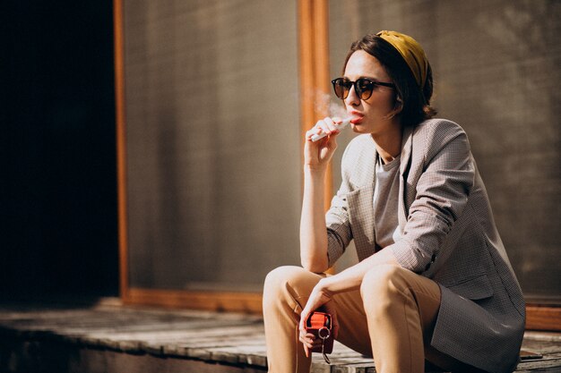 Young woman sitting and smoking ecigarette