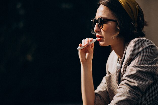 Молодая женщина сидит и курит ecigarette