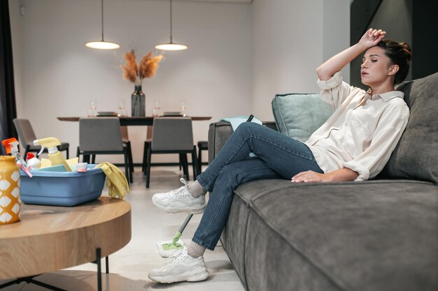 Young woman sitting on the sofa and looking tired