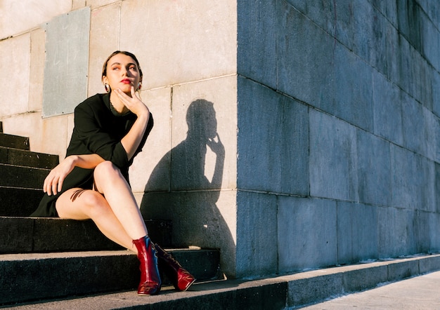 Young woman sitting on staircase in sunlight