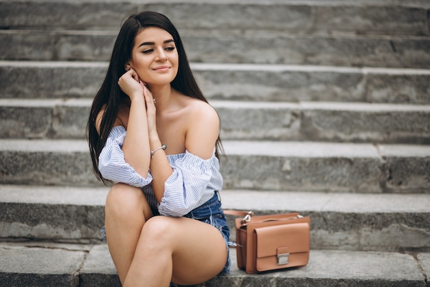 Young woman sitting on the stairs by the building