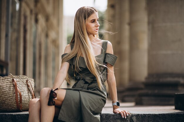 Young woman sitting on the stairs of an old bvuilding