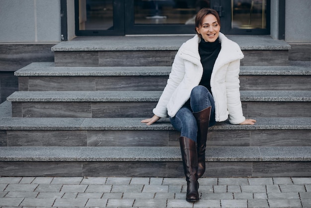 Free photo young woman sitting on stairs outdoors