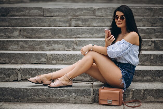 Young woman sitting on the stairs talking on the phone