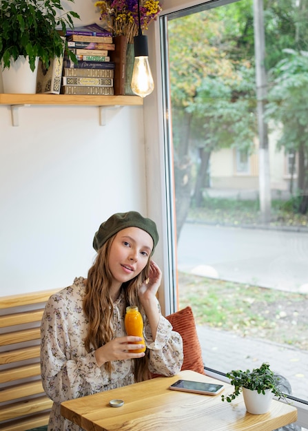 Young woman sitting at table holding fresh juice bottle