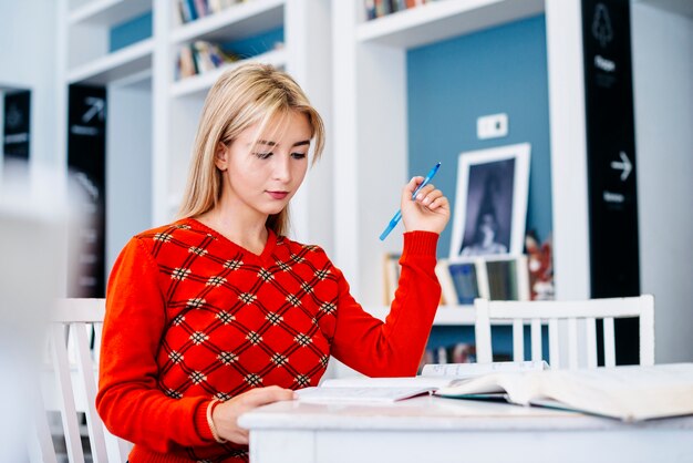 ペンを持っているテーブルに座っている若い女性