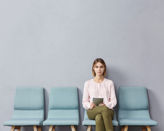 Free photo young woman sitting in waiting room