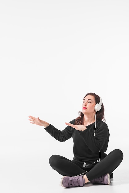 Young woman sitting with crossed leg enjoying music on headphone dancing