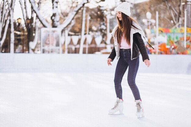 Молодая женщина катается на коньках на катке в центре города