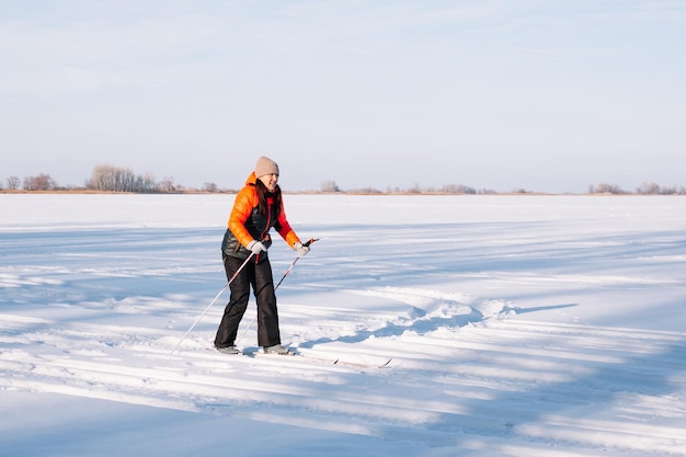 Young woman skiing in winter brunette in winter suit is doing sports in nature on background of fore...