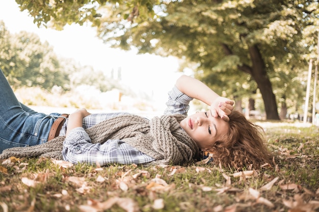 Foto gratuita giovane donna che dorme sull'erba del parco