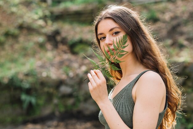 Young woman smelling on a leaf in forest