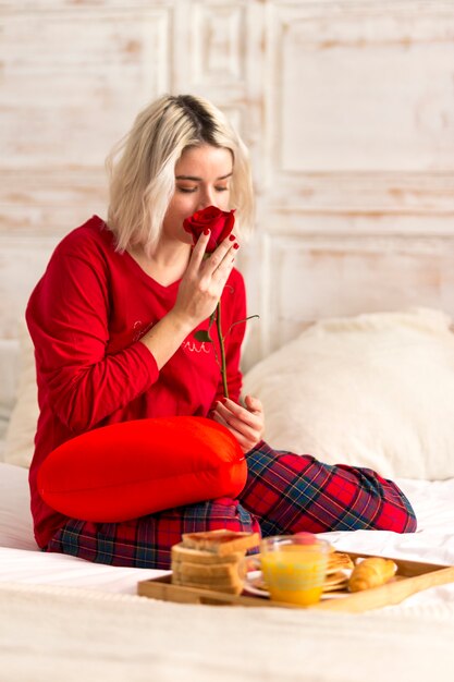 Young woman smelling red rose flower