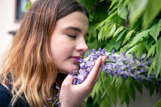 A young woman smells a wisteria flower