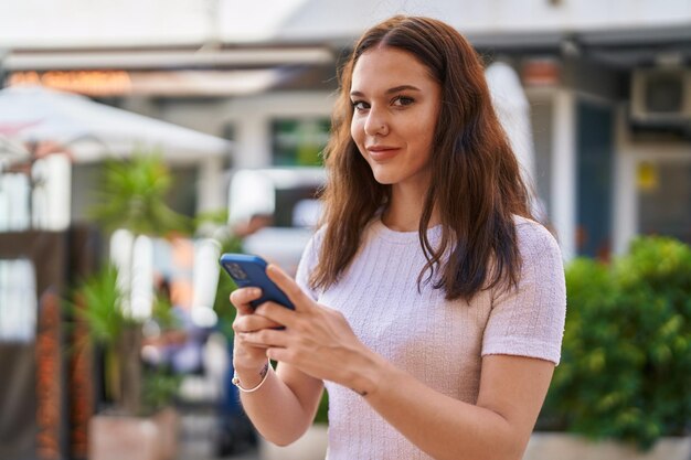 通りでスマートフォンを使って自信を持って微笑む若い女性