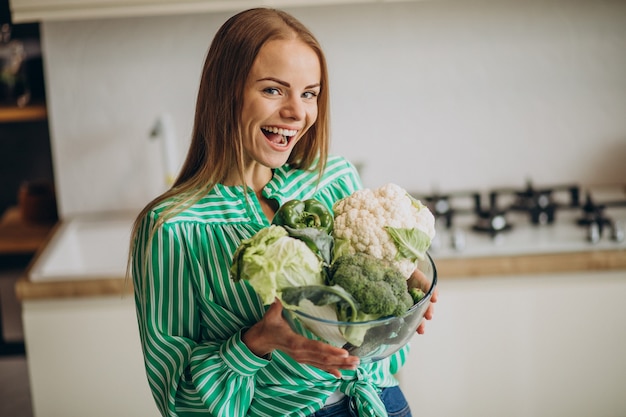 Молодая женщина улыбается и держит цветную капусту