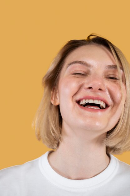 Young woman smiling isolated on yellow