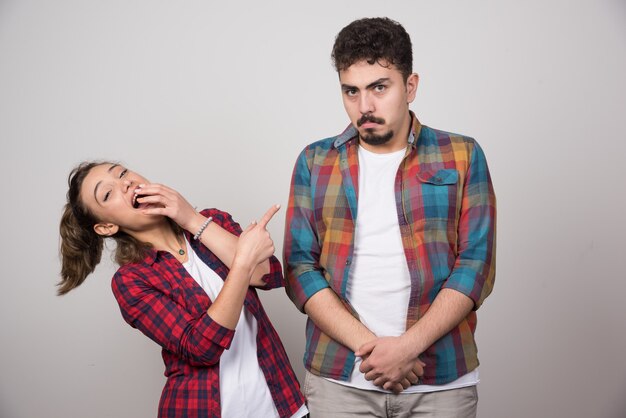 Young woman smiling and pointing at offended man .