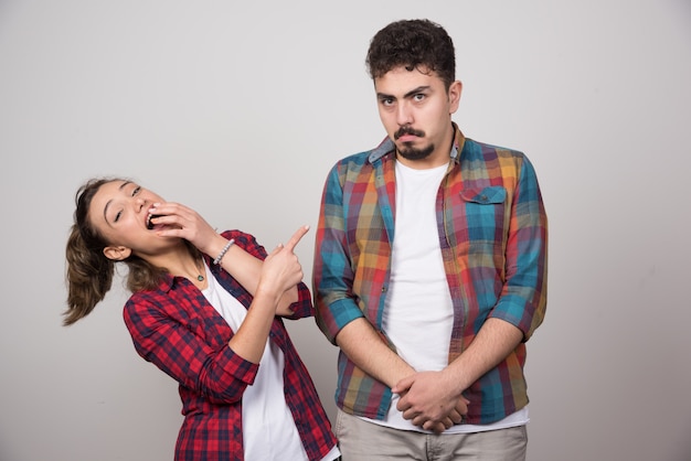 Young woman smiling and pointing at offended man .