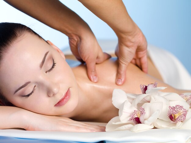 Young woman in spa salon having massage of  shoulder - horizontal