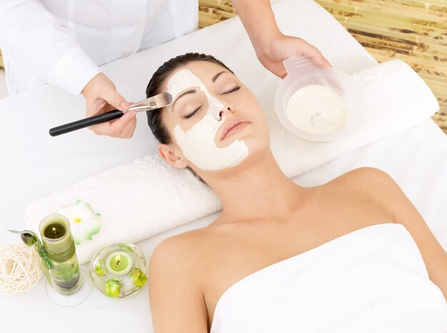 Young woman at spa salon with cosmetic mask on face. High angle photo