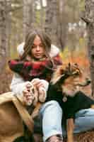 Бесплатное фото Молодая женщина проводит время вместе со своей собакой в лесу