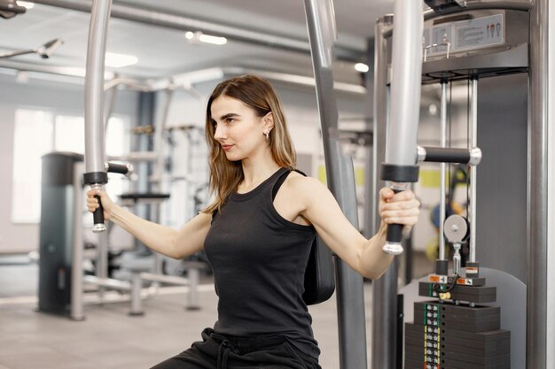 체육관에서 특별한 장비로 운동을 하는 운동복을 입은 젊은 여성
