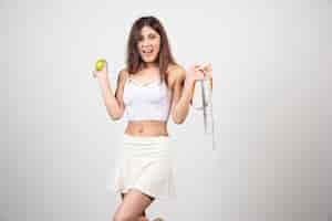 Free photo a young woman in sportswear holding a fresh apple with waist width.