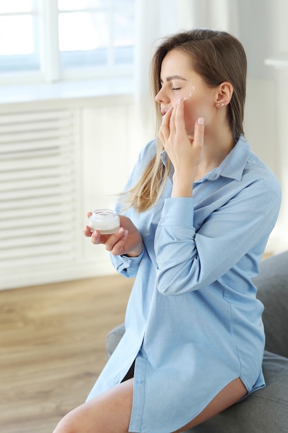 Young woman spreading facial cream. Skin care concept.