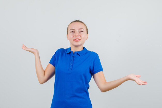 青いTシャツで手のひらを広げて陽気に見える若い女性