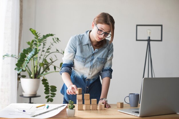 オフィスの仕事机の上の若い女性スタッキング木製ブロック