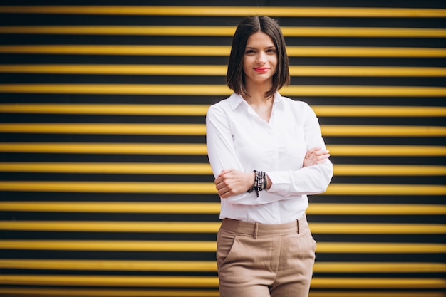 Young woman standing by the yellow wall