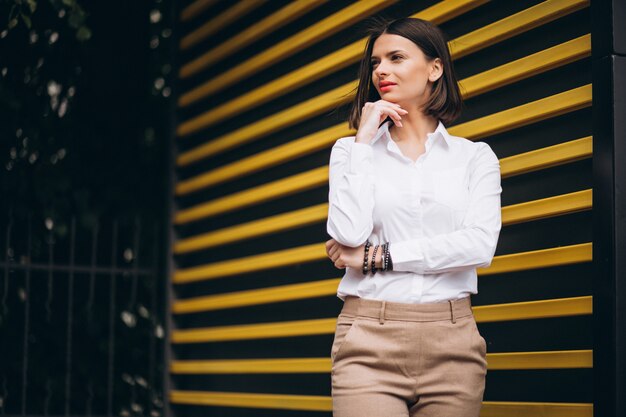 Young woman standing by the yellow wall