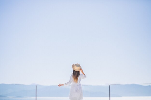 Молодая женщина, стоя сзади и глядя на море
