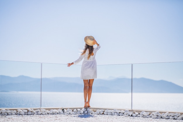 Free photo young woman standing from the back and looking at the sea