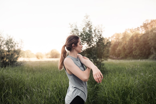 Молодая женщина, стоя в травянистом поле, протягивая руку