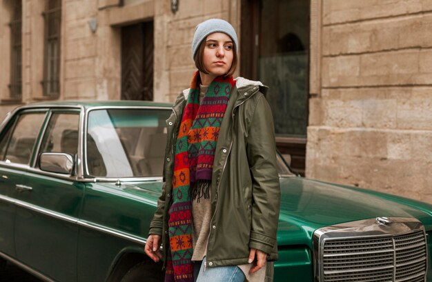 Young woman standing next to green car