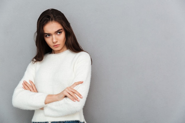 Young woman standing on grey wall