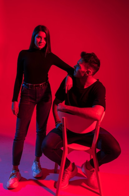 Young woman standing near man on chair 