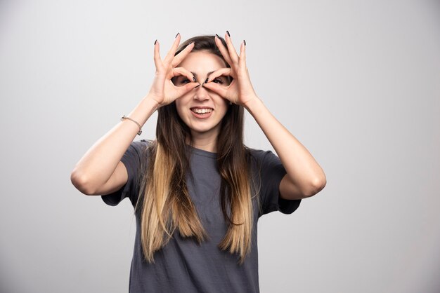 灰色の背景の上に立ってポーズをとる若い女性。高品質の写真