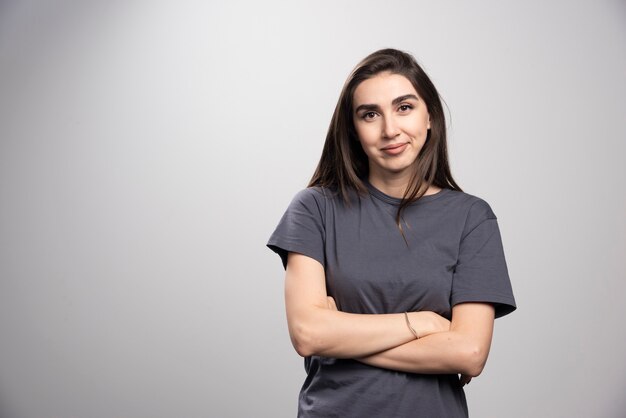 Young woman standing and posing over a gray background .