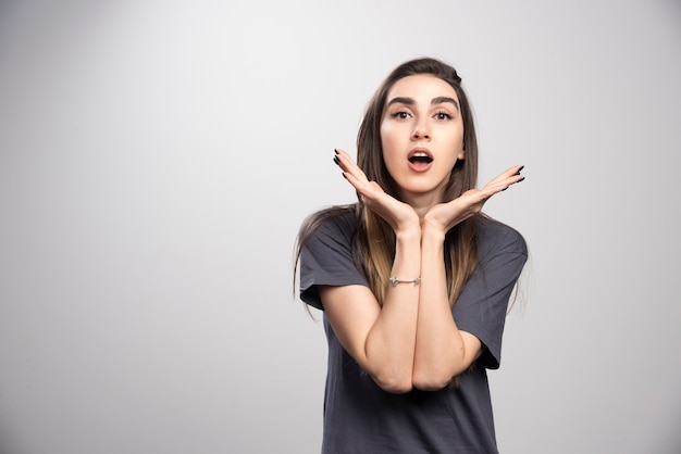 Young woman standing and posing over a gray background.