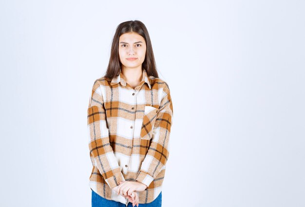 young woman standing serious on white wall.