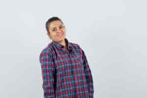 Free photo young woman standing straight and posing at camera in checked shirt and looking pretty , front view.